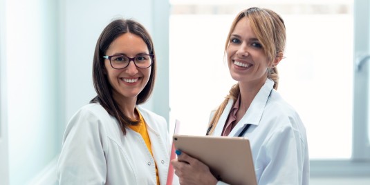 zwei Ärztinnen mit Tablet lächeln