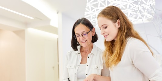 Ärztin und MFA am Empfang schauen auf ein Formular