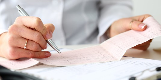 Ärztin untersucht EKG-Ergebnis