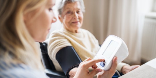 Ärztin misst Blutdruck einer Seniorin