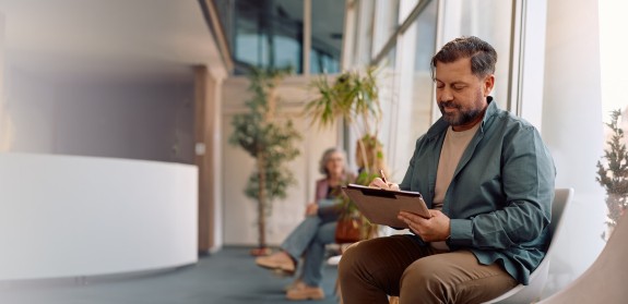 Mann im Wartebereich hält Ipad in der Hand