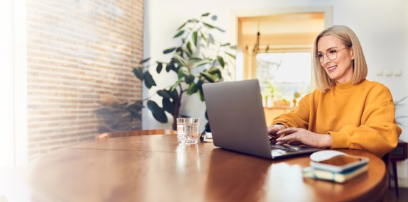 Frau sitzt daheim am Laptop